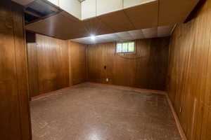 Below grade area featuring wood walls and a paneled ceiling