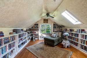 Living area with light wood-style flooring, a textured ceiling, and vaulted ceiling