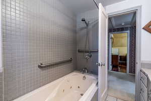 Full bath featuring a combined bath / shower with jetted tub, vanity, and tile patterned floors