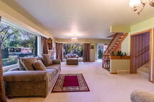 Carpeted living area featuring a chandelier and stairs