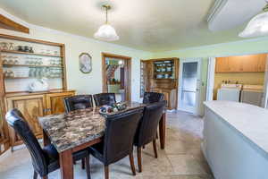 Dining room with ornamental molding, washer and clothes dryer, and light tile patterned floors