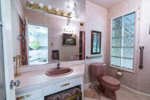 Half bath with vanity, tile patterned floors, and wallpapered walls