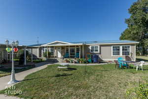 View of front of house with a front lawn, a metal roof, and a porch