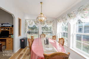 Dining space with healthy amount of natural light, light wood finished floors, and a chandelier
