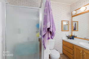 Full bathroom featuring wallpapered walls, vanity, a shower stall, and dark tile patterned floors