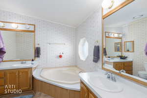 Bathroom with a garden tub, two vanities, ornamental molding, and wallpapered walls