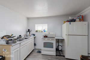 ADU Kitchen featuring white appliances, light wood-style flooring, white cabinetry, light countertops, and ornamental molding