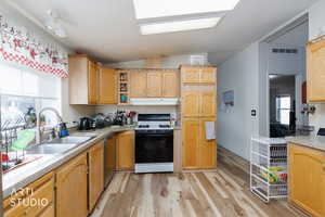 Kitchen with light wood-style flooring, vaulted ceiling, gas range gas stove, light countertops, and open shelves
