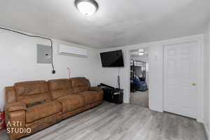ADU Living room featuring electric panel, wood finished floors, and a wall mounted AC