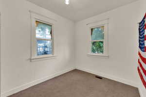 Carpeted spare room featuring baseboards