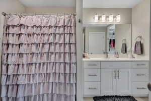 Full bathroom featuring vanity, a walk in closet, and curtained shower