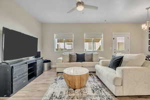 Living area featuring light wood-type flooring, a chandelier, and ceiling fan