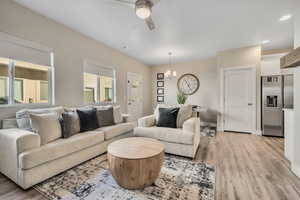Living room featuring light wood-style flooring, ceiling fan, a chandelier, and recessed lighting