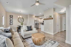 Living room with light wood-style floors, a chandelier, a ceiling fan, and recessed lighting