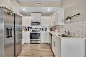 Kitchen featuring stainless steel appliances, white cabinets, tasteful backsplash, light stone countertops, and recessed lighting