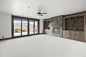 Basement living room with HUGE sliding doors, a gas fireplace, light carpet, built in features, ceiling fan, and recessed lighting