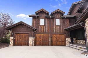 Chalet / cabin with stone siding, driveway, and board and batten siding