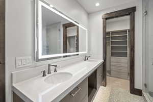 Bathroom featuring a stall shower, a spacious closet, double vanity, and recessed lighting leads to a walk in closet