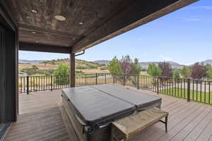 TREX Deck featuring a hot tub, a mountain view, and a yard