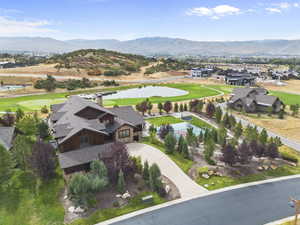 Aerial view of property and sports court  area featuring a golf course, pond and mountain view
