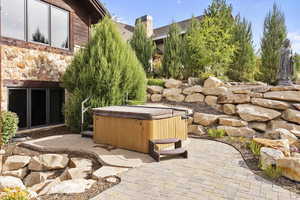 View of patio / terrace featuring a hot tub and waterfall