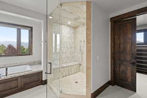 Full bath with a mountain view, a bath, a steam shower stall with custom tile pattern.