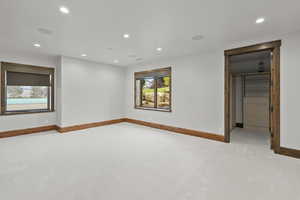 Bedroom featuring recessed lighting, light colored carpet, and a private bath with a walk in closet