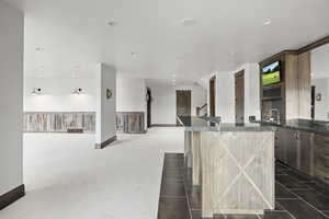 Basement Kitchen featuring dark stone counters, open floor plan, tile flooring, a center island, and recessed lighting