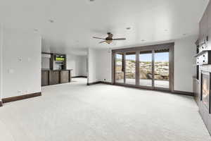 Basement living room with light colored carpet, a tiled fireplace, ceiling fan, and recessed lighting