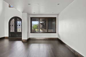 Large Dining room with dark wood-style floors, arched walkways, and adjacent Entry with french doors