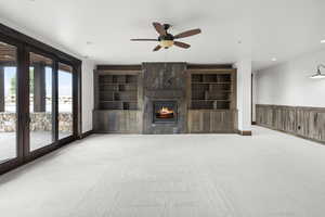 Basement living room with a ceiling fan, light carpet, a gas fireplace, and recessed lighting