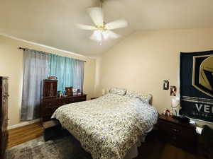 Bedroom featuring dark wood-type flooring, vaulted ceiling, and ceiling fan