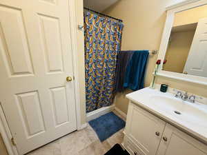 Bathroom with vanity, light tile patterned floors, and a shower with curtain