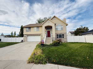 Bi-level home featuring brick siding, concrete driveway, a chimney, and an attached garage