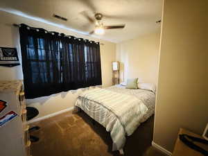 Bedroom featuring a ceiling fan, carpet flooring, and a textured ceiling