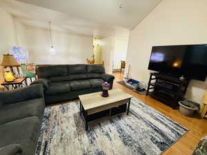 Living area with light wood-style flooring and high vaulted ceiling