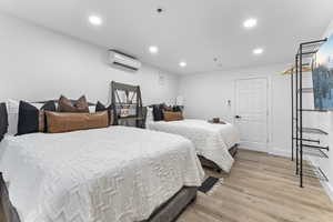 Bedroom featuring light wood-type flooring, recessed lighting, and an AC wall unit