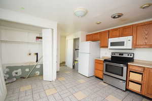Kitchen with white appliances, light countertops, and brown cabinets