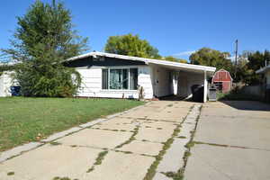 View of front of home featuring concrete driveway, a front yard, and a carport