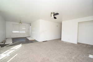 Unfurnished living room with carpet floors and ceiling fan