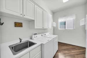 Washroom featuring dark wood finished floors, cabinet space, and washer and clothes dryer