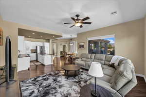 Living area with dark wood-type flooring, ceiling fan, a textured ceiling, and recessed lighting