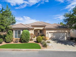 View of front of house with stucco siding, an attached garage, concrete driveway, a tiled roof, and a front lawn