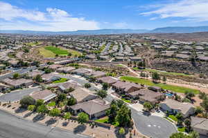 Aerial perspective of suburban area featuring a mountainous background and a golf course