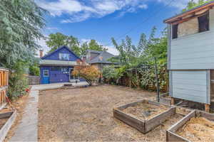 Rear view of property featuring a vegetable garden, a fenced backyard, and a patio area