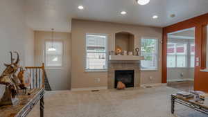 Carpeted living area with a tile fireplace and recessed lighting