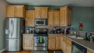 Kitchen featuring appliances with stainless steel finishes, light brown cabinets, and backsplash