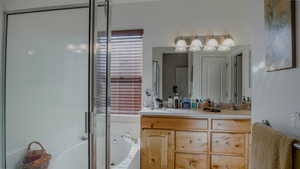 Bathroom featuring vanity, a bath, and a shower stall