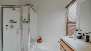 Bathroom with a shower stall, vanity, and a bath