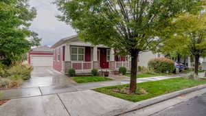 View of front facade with a porch, a garage, a front yard, and concrete driveway